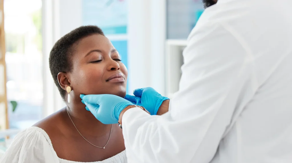 A doctor checks a woman's thyroid during a medical examination in a doctor's office.