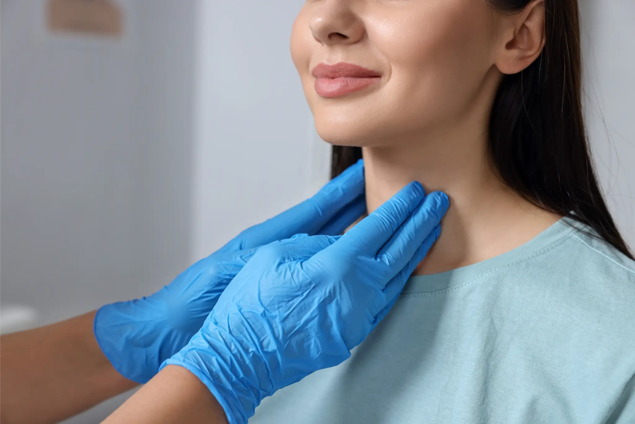 A woman receiving a thyroid exam at a medical facility